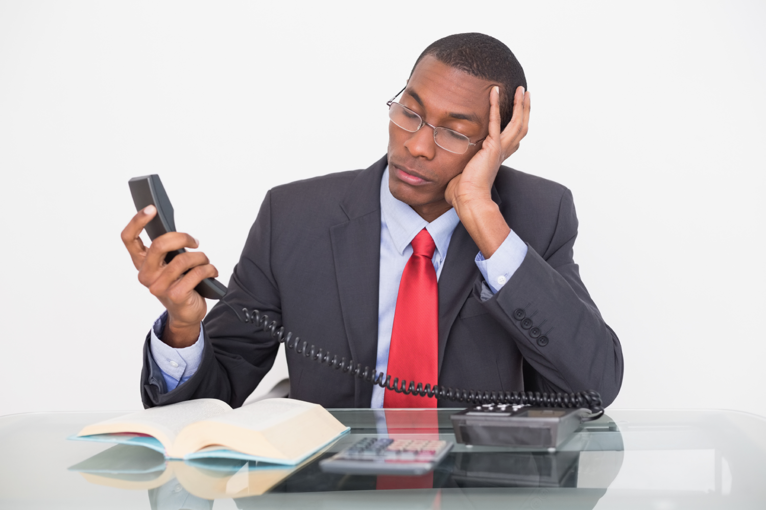 Young tensed young Afro businessman looking at telephone receiver against white background Young tensed young Afro businessman looking at telephone receiver against white background<br />